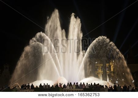 BARCELONA, SPAIN - JULY 29, 2016: Barcelona (Catalunya Spain): the Magic Fountain (Fuente Magica Font Magica) of Montjuic with plays of colorful lights at evening and people in silhouette watching at the show