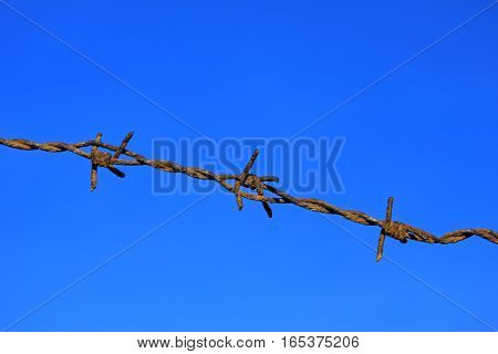 rusty barbed wire against deep blue sky