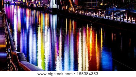 The reflection of light waves in the water Colored city lights reflected on water surface in night.