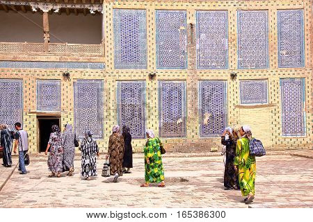 KHIVA, UZBEKISTAN - MAY 3, 2011: Uzbek women walking in the courtyard of Tosh Hovli palace