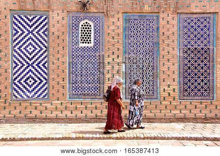 KHIVA, UZBEKISTAN - MAY 3, 2011: Uzbek women walking in the courtyard of Tosh Hovli palace