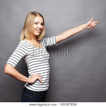 Happy smiling beautiful young woman showing copyspace, visual imaginary or something, or pressing virual button over grey background