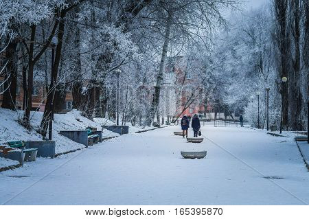 Winter street of a small town urban alley people trees frost