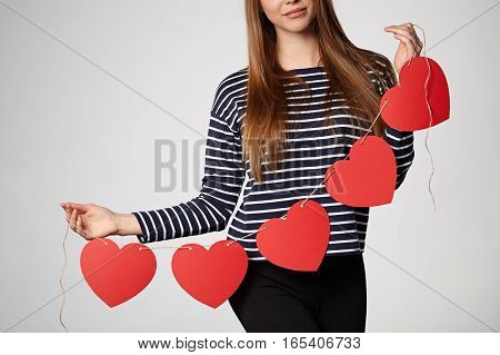 Croped image of a woman holding garland of five red paper hearts shape - blank copy space for letters or text