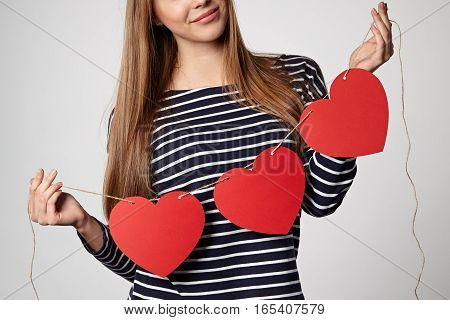 Croped image of a woman holding garland of three red paper hearts shape - blank copy space for letters or text