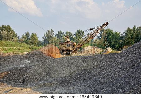 Old crawler-mounted excavator in gravel canyon. Industry.