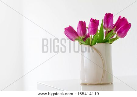 Beautiful Fresh Spring lila Tulips in Vase on bright background. Spring easter or Mother's Day Concept.
