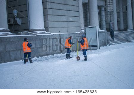 Three women in uniform clean snow at the station