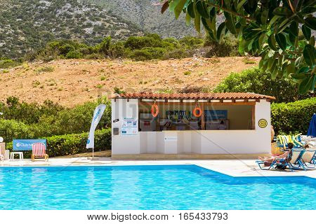 Bali Greece - April 29 2016: Relax and sunbathe by pool with clear blue water in Resort hotel Atali Village 4 star. Tourists in swimwear have rest by pool in middle of day. Bali Rethymno Crete Greece