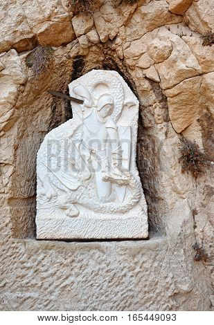 Bas-relief in the Castle of Santa Barbara ruined chapel. A warrior with sword fighting with a dragon. Alicante