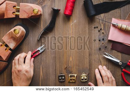 cobbler with tools work process dark background top view with hands
