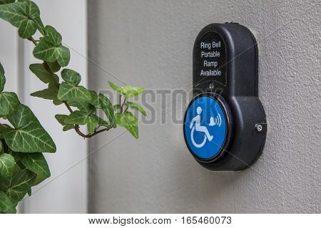 Portable wheelchair ramp bell button on a wall.