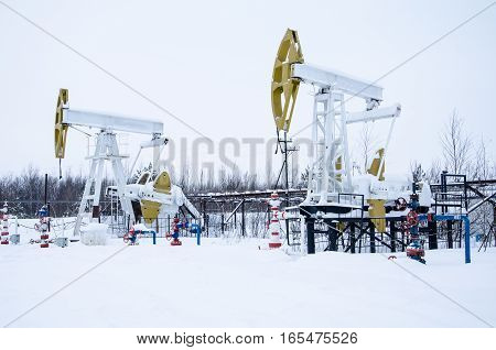 Group of oil pumps and wellheads in the oilfield during winter. Oil and gas concept.
