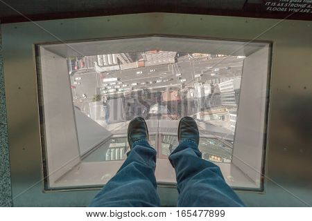 Auckland New Zealand- December 12 2013. A man step on traveling glass's floor of NZ sky tower and looking down New Zealand city.