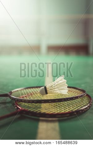 Badminton ball (shuttlecock) and racket on court floor. Badminton sports. Play badminton. Badminton exer cise. Badminton tournament. Badminton training. Badminton feather. Badminton health. Shuttle badminton. Badminton Vintage.