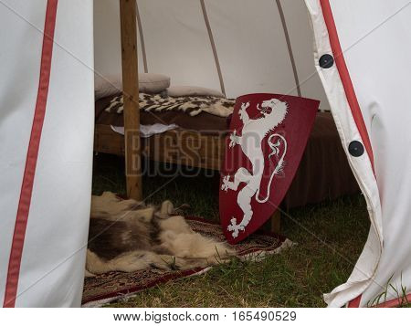 Inside Medieval Tent: Wodden Bed Carpet and Red Shield with Dragon - Medieval Event Reconstruction
