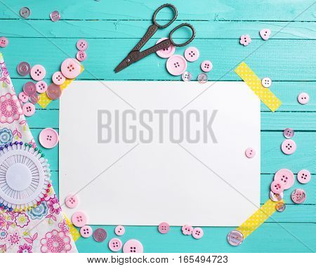 Sewing thread - buttons scissors fabric and empty tag on turquoise wooden background. Selective focus. Scrapbboking. Flat lay. Place for text.