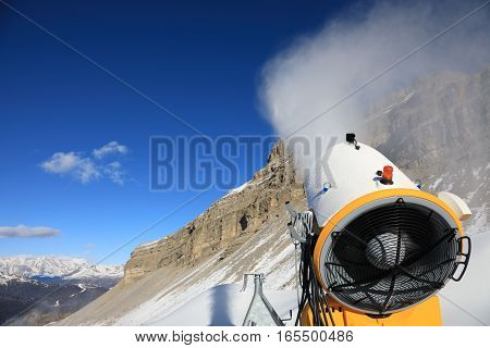 Snow cannon against the blue sky. Snow-making is the production of snow by forcing water and pressurized air through a 