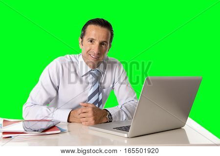 40 to 50 years old senior businessman working on computer laptop sitting at office desk looking confident relaxed and successful isolated on green chroma key screen background