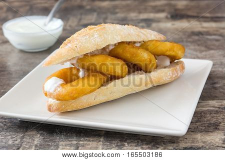 Calamari sandwich with aioli on wooden table