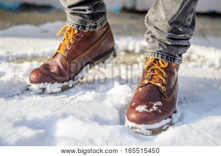 Man walks in the snow. Feet shod in brown winter boots. Winter walks concept