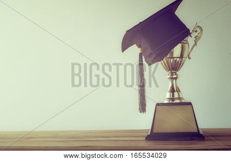 Graduation Cap With Champion Golden Trophy On Wood Table With Copy Space Ready For Your Design.gradu