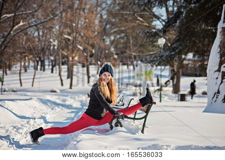 Beautiful woman doing yoga outdoors in the snow at winter time