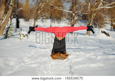 Beautiful woman doing yoga outdoors in the snow at winter time