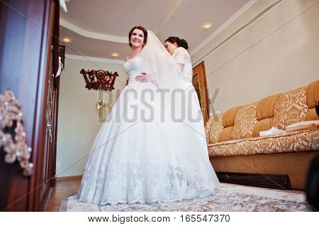 Bridesmaids Helping Dressed Bride On Wedding Day At Morning.