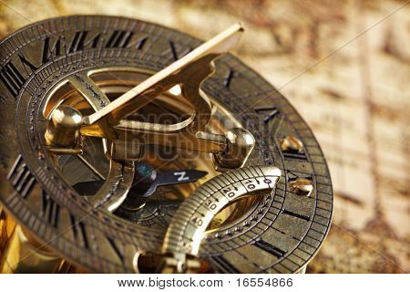 Brújula de bronce antiguo y reloj de sol en mapamundi