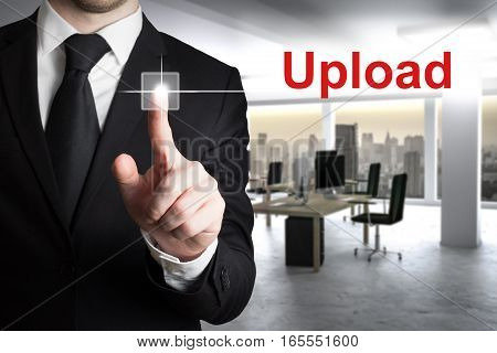 businessman in large modern office pushing button upload
