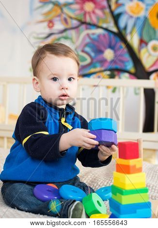 Cute little kid boy playing with lots colorful wooden blocks toy at home.Toddler boy play with toys. Adorable little boy playing with colorful cubes. Happy child playing colorful blocks.