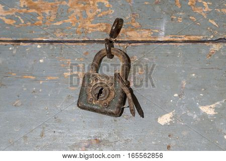 detail of rusty padlock closing an old wooden toolbox, timeworn paint