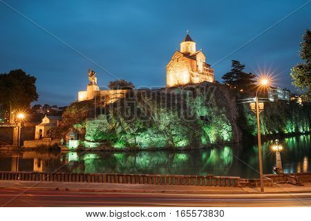 Night Evening Illuminated View Of The Metekhi Church And The Equestrian Statue Of King Vakhtang Gorgasali On The Metekhi Cliff In Old Historic District Of Tbilisi Georgia. Blue Hour. Blue Evening Sky.