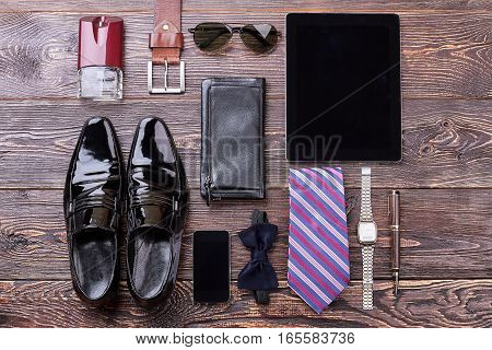Men's accessories on wooden background. Black shoes and bow tie. Expensive look for man.