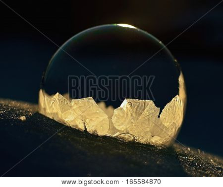 Frozen soap bubble. Cold winter liquid ball experiment. Freezing water with icy patter texture