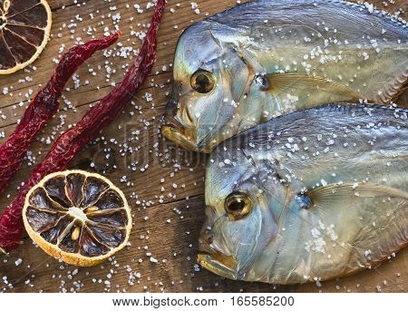 Two fish Cold smoked Vomero. Red pepper. Dried lemon. Are scattered sea salt. On a wooden background. Top view
