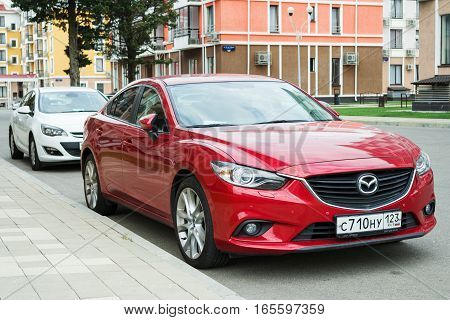 Sochi, Russia - October 11, 2016: New red Mazda 6 (Atenza) parked near modern houses. The Mazda6 has sold over one million units worldwide since its introduction hitting this sales milestone faster than all previous Mazdas.