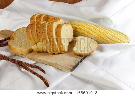 bread made from corn on the white fabric. Slices of corn bread laying on a chopping Board and Sweet corn cobs