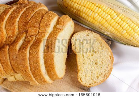 bread made from corn on the white fabric. Slices of corn bread laying on a chopping Board and Sweet corn cobs