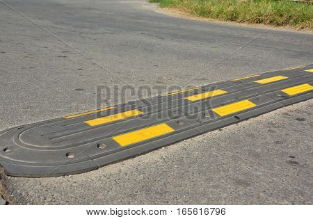 Traffic safety speed bump on an asphalt road. Speed bumps (or speed breakers) are the common name for a family of traffic calming devices.