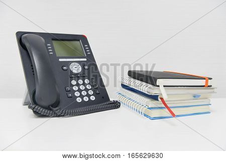 Black IP Phone and stack of books