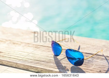 Blie Sunglasses on wooden decking by seaside