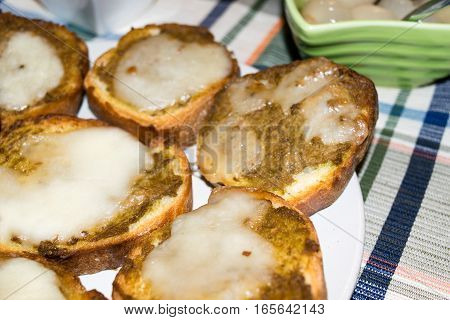 slices of toasted bread season with olive paste and melted cheese