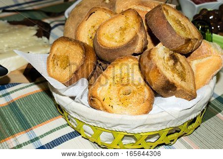 Basket filled with bread and slices of toasted bread seasoned with oil and pepper