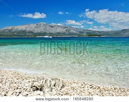 Sea view from the beach with sailboat and mountains