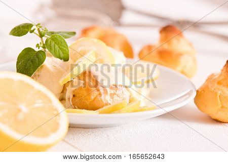 Lemon Profiteroles with custard cream on white dish.