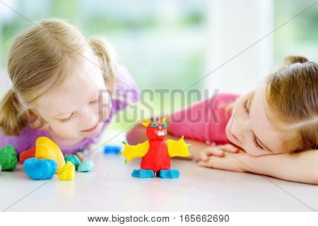 Two Cute Little Sisters Having Fun Together With Colorful Modeling Clay At A Daycare