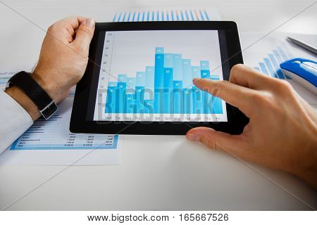 Business person analyzing financial statistics displayed on the tablet