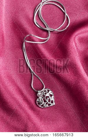 Silver heart shaped medallion on pink satin